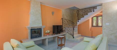 Un salon avec une cheminée, un canapé et un escalier.