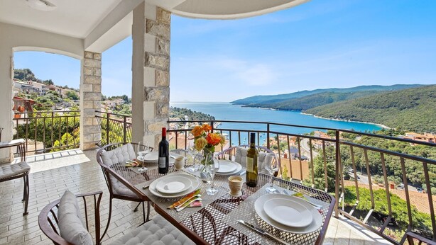 A balcony with a table set for dining, overlooking a scenic coastal view. - Lady M Gold - Balcony and Sea View (Rabac)