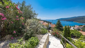 A coastal view with a stone staircase leading down to a road, surrounded by lush greenery and pink flowers. - Lady M Gold - Balcony and Sea View (Rabac)