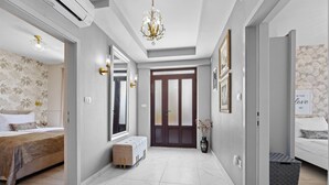 A modern hotel room with a large bed, a sitting area, and a hallway leading to a door. - Lady M Gold - Balcony and Sea View (Rabac)