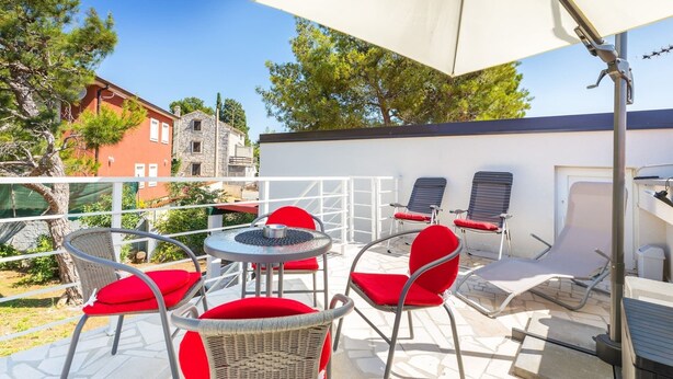 An outdoor patio with wicker chairs and red cushions, a white umbrella, and a grill area. - Villa Ziziphus - Private Pool with Jacuzzi (Premantura)