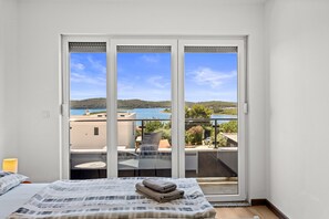 A bedroom with a bed, a view of a balcony, and a door to an outdoor area.