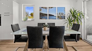 A modern dining area with a glass table, black chairs, a view of the sea, and a potted plant. - Villa Pura Vida - Private Pool, Sea View (Pomer)