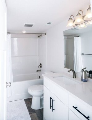 A modern bathroom with a bathtub, toilet, and vanity.