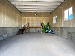 A spacious indoor area with a concrete floor, a staircase, and a ceiling with exposed beams.