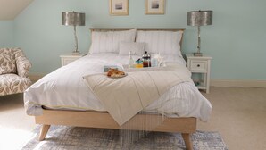 Un dormitorio con cama, mesitas de noche, lámparas, una silla y alfombra.