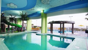 Une piscine avec un toboggan, des palmiers et un kiosque.