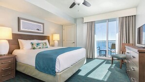 Une chambre d’hôtel avec un lit, un bureau, une chaise et un balcon donnant sur la mer.