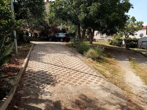 A paved pathway leading to a building with a car parked nearby.