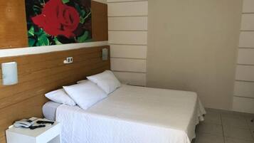Una cama bien hecha con ropa de cama blanca en una habitación de hotel.