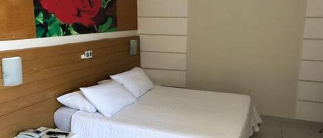 A neatly made bed with white bedding in a hotel room.