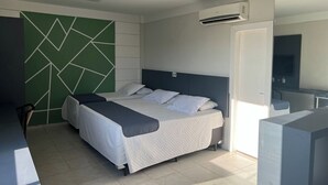 A modern bedroom with a bed, a green geometric wall, an air conditioning unit, and a large mirror. - Veneza Palace Hotel (Cuiabá)