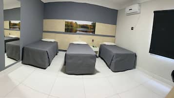 A room with three beds, a small table, and a large mirror.
