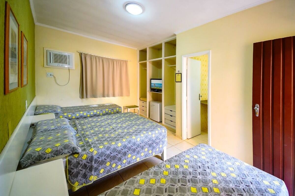 Ein Hotelzimmer mit zwei Betten, einem Kleiderschrank, einem Fernseher und einem Badezimmer.