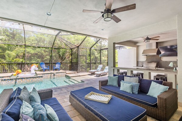 A poolside area with a glass-enclosed patio, outdoor seating, and a barbecue area.