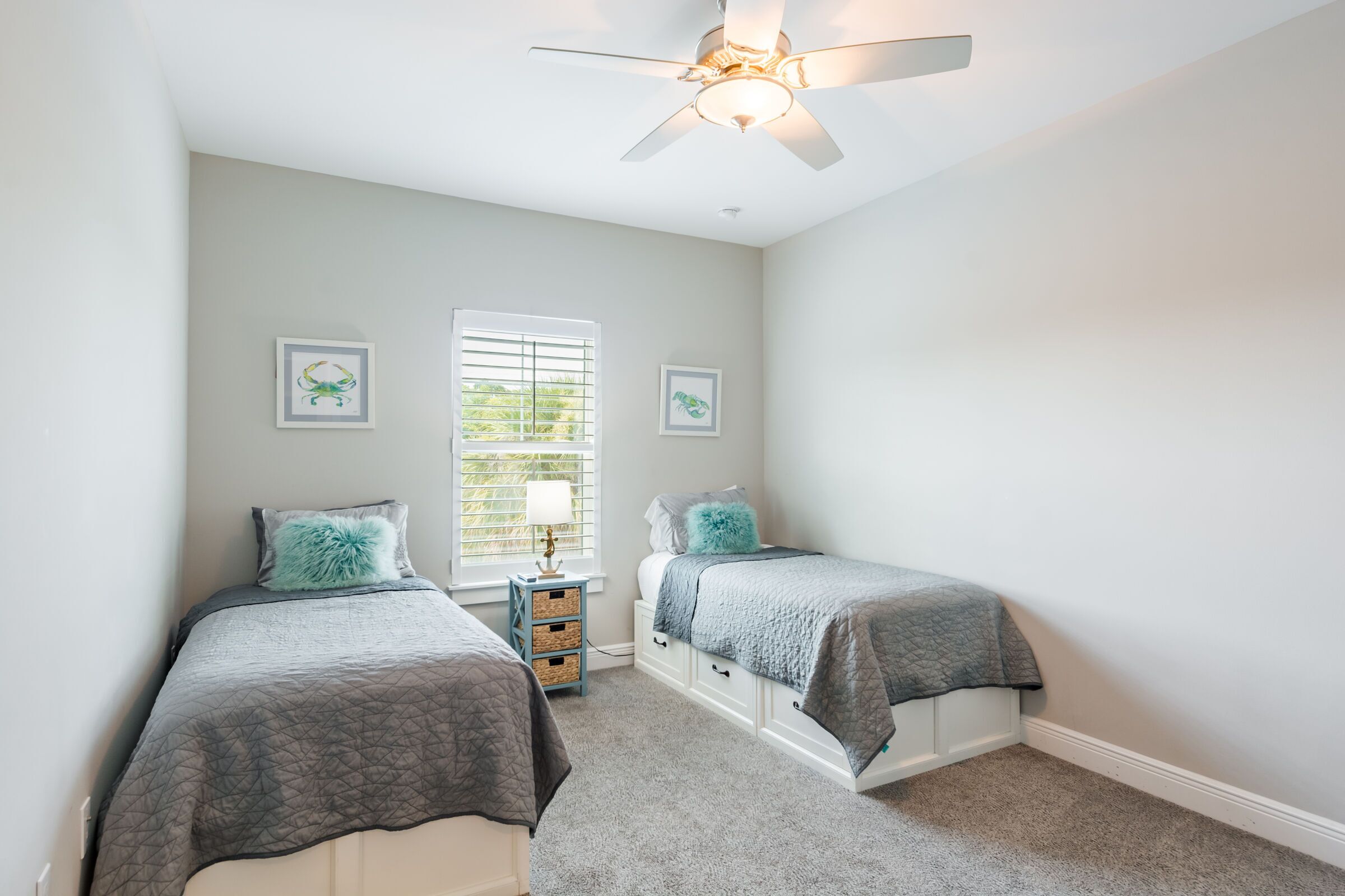 A bedroom with two beds, a ceiling fan, and a window with blinds.