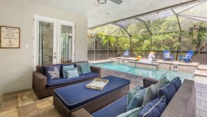 An outdoor pool area with wicker furniture, a ceiling fan, and a sign that reads "Work Captain Play Pirate." - The Seagrape Villa -Family Friendly- Luxury Accommodation in Paradise (Sarasota)
