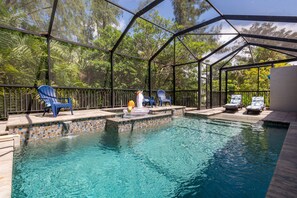 A covered swimming pool with clear water, surrounded by blue chairs and a decorative fountain.