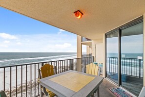 Een balkon met uitzicht op de oceaan, een tafel, stoelen en een klein raam.