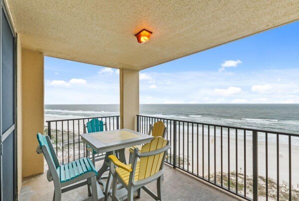 Een balkon met een tafel en stoelen, met uitzicht op de oceaan.