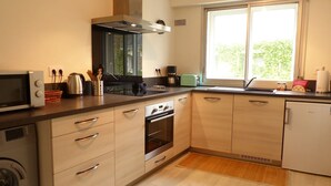 Eine moderne Küche mit Mikrowelle, Herd, Backofen und Spüle. Ein Fenster sorgt für natürliches Licht und bietet einen Blick auf Grünflächen.
