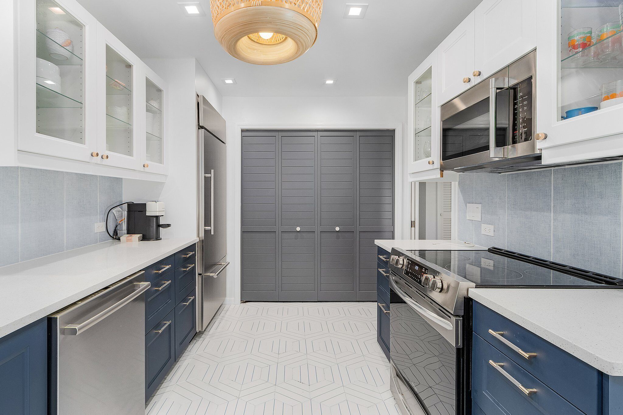 A modern kitchen with white and blue cabinets, a stainless steel stove, and a microwave.