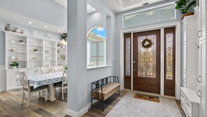 Un intérieur moderne comprenant un coin repas, des étagères intégrées, un banc et une porte décorée d’une guirlande.