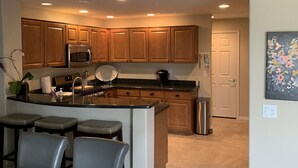 A modern kitchen with wooden cabinets, a central island, and a dining area with bar stools. - Beautiful Grayhawk Condo!  Negotiated rates and FLEXIBLE Dates-contact owner (Scottsdale)