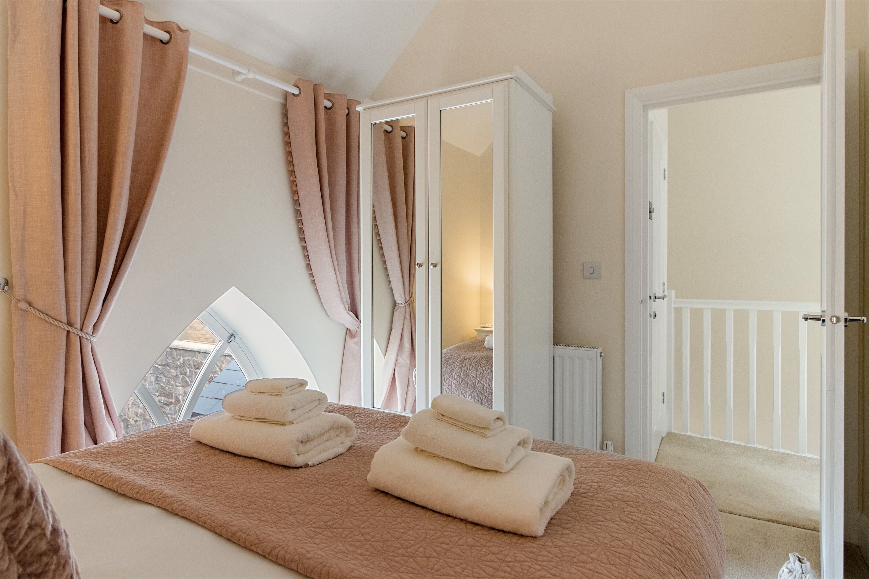 Une chambre à coucher avec un grand lit, une armoire, une fenêtre avec des rideaux et une vue sur l’extérieur.