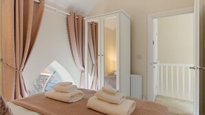 Un dormitorio con una cama grande, un armario, una ventana con cortinas y vistas al exterior.