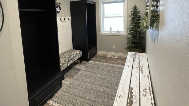 A room with a built-in bench, a small Christmas tree, and a window with natural light. - "Highlander" House 4 Bedroom, 3 Bath- Ackerman Valley (Devils Lake)