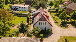 Ett stort hus med ett rött tak, omgivet av en välskött gräsmatta och träd.