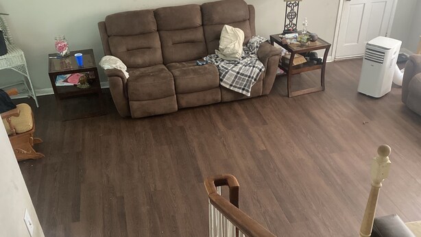 A living room with a brown sofa, a small table with a lamp, and a white door in the background. - A great peaceful apartment (Mississippi Biloxi)