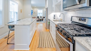 Una cocina moderna con armarios blancos, una isla central, una estufa y un microondas.
