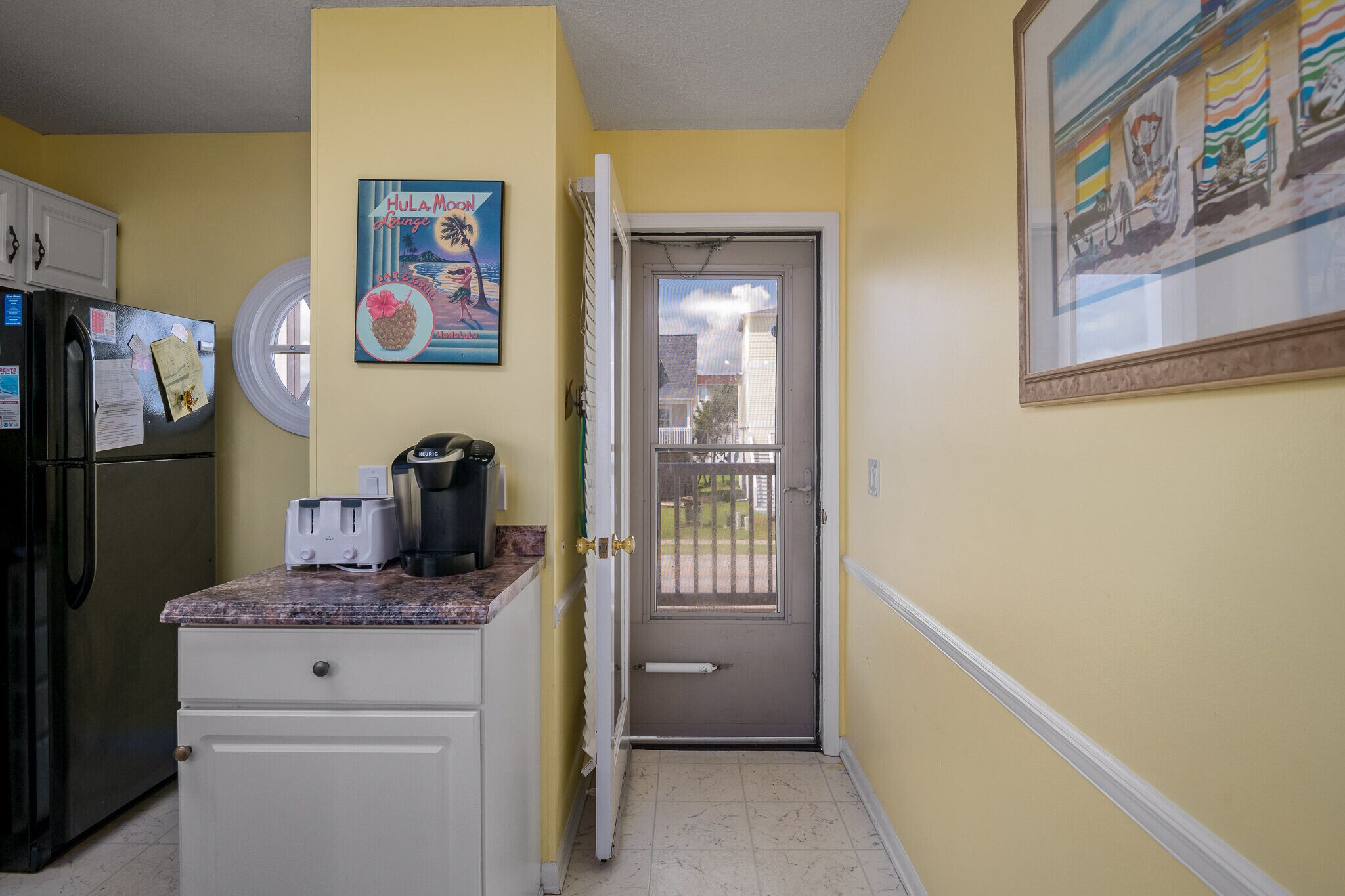 A kitchen with a refrigerator, a toaster, and a coffee maker on the counter.