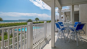 A balcony with white railings overlooking a pool and beach. - "Waters Edge 427-D" - Oceanfront Condo w/ Community Pool, 2 Bedrooms / 2 Bathrooms (Holden Beach)