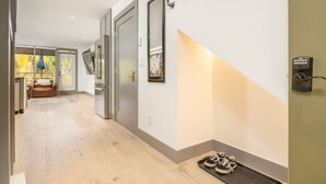 A hallway with a shoe rack, a door, and a wall-mounted security device.