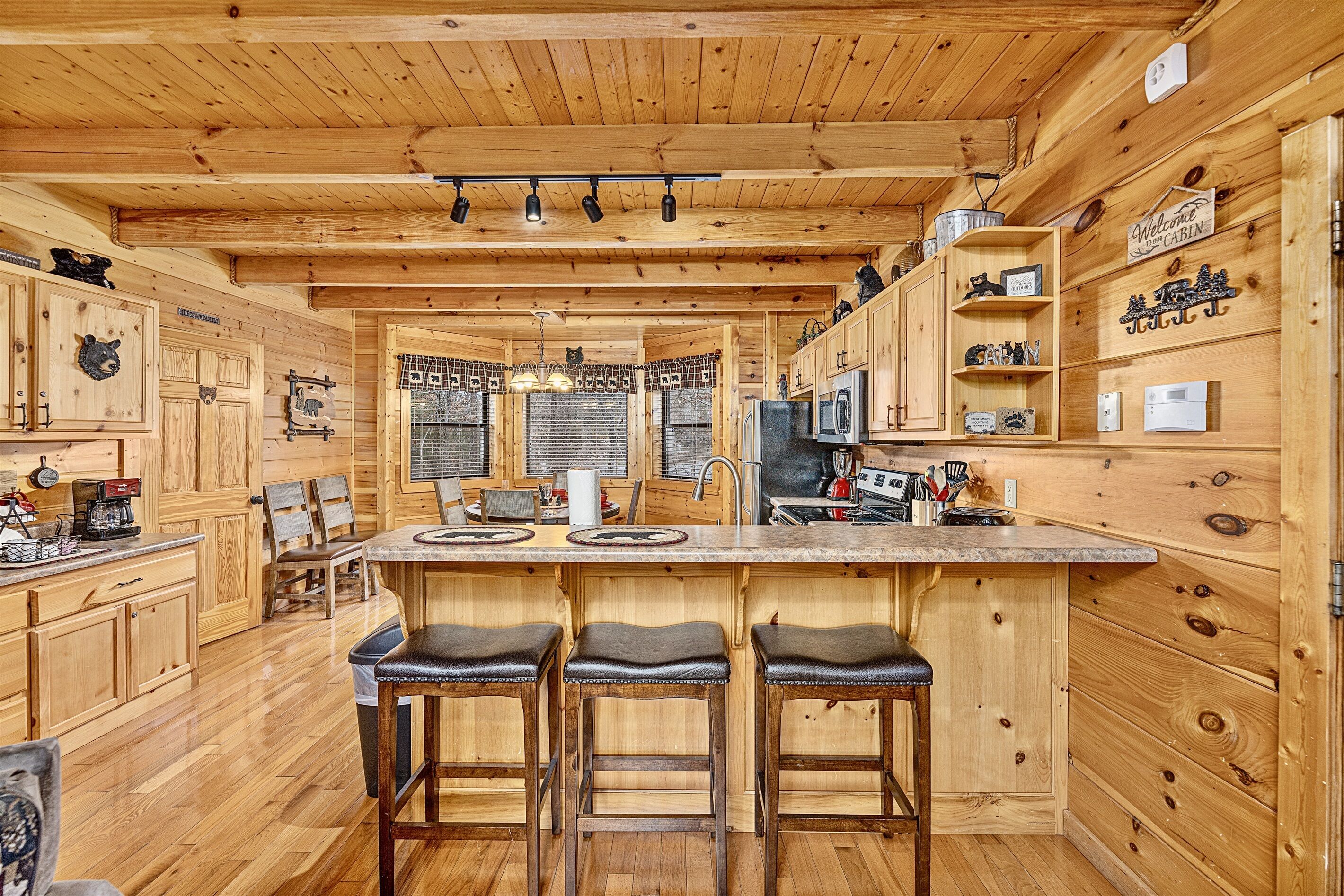 Een houten chalet interieur met een bar in het midden, houten kastjes en een keukenhoek.