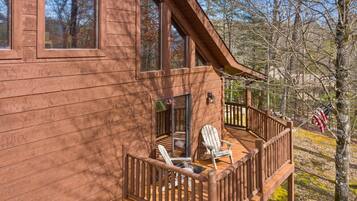 Een houten chalet met een terras, twee Adirondack-stoelen en een Amerikaanse vlag.