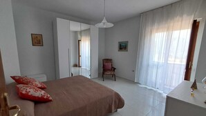 Un dormitorio con cama, una silla, un armario y un escritorio.
