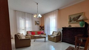 Una sala de estar con sofá, dos sillones, una mesa de centro, chimenea y un cuadro en la pared.