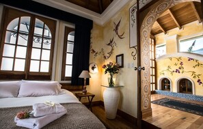 Hotelkamer met een bed, een vaas met bloemen, een lamp en uitzicht op een terras.