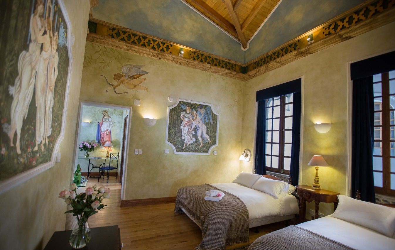 A hotel room with two beds, a dining area, and a mural on the wall.