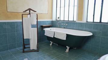A bathroom with a freestanding bathtub, a towel rack, and a window with bars.