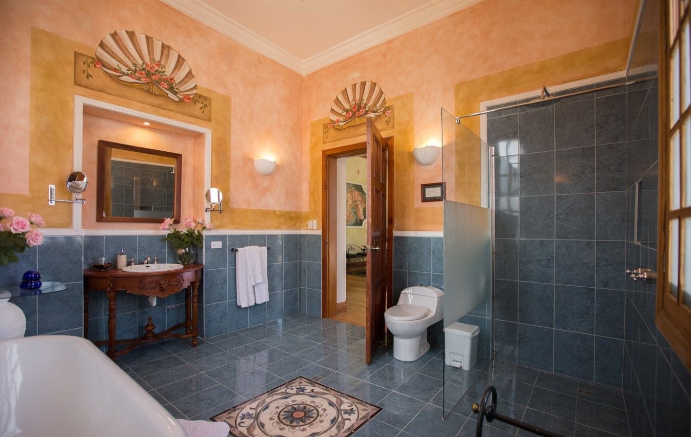 A bathroom with a bathtub, a toilet, a vanity with a mirror, and a shower area.