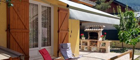 A wooden deck with two chairs, a covered patio area, and a mountain view in the background.