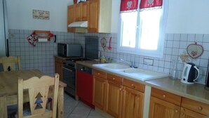 A kitchen with wooden cabinets, a sink, a stove, and a dining table with chairs.
