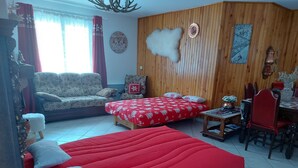 A room with a large bed, a sofa, a dining table, and a chair.