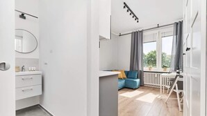 Ein modernes Apartment mit Bad, Wohnbereich mit Sofa und Tisch sowie einem Balkon.