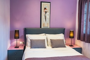 Un lit bien fait, avec deux oreillers, une œuvre d’art encadrée au-dessus, et deux lampes de chevet sur les tables de nuit.
